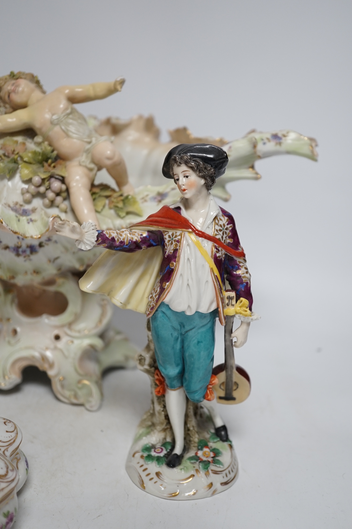 A porcelain shell-shaped centrepiece, a Dresden pill box, a pair of taper holders and a porcelain figure, tallest 21cm